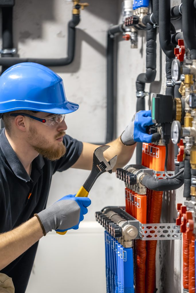 Technician adjusts heating manifold and valves in a boiler room, Stylezing UK plumbing & electrical services in London