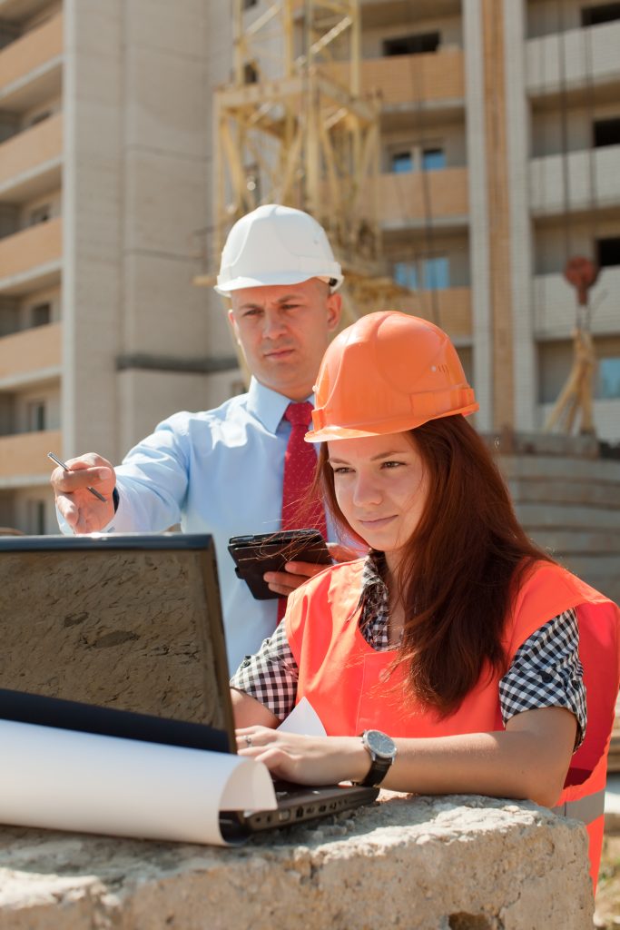 Construction team reviewing plans on a laptop at a building site in London